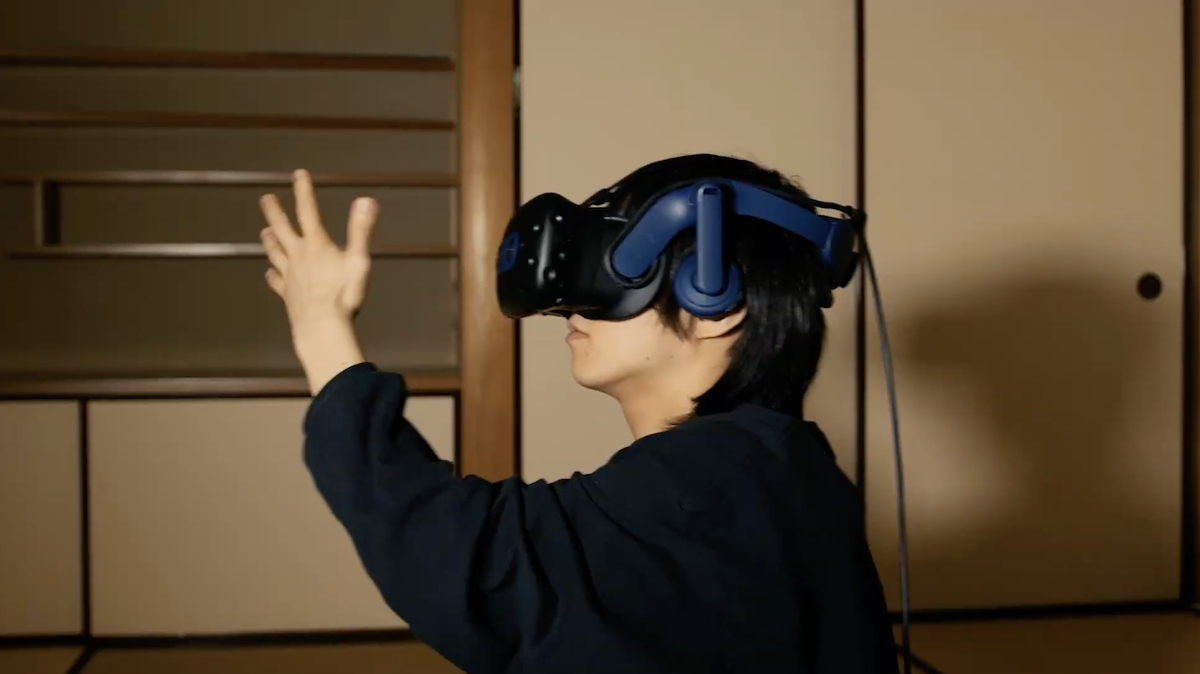 VRヘッドセットを着けて手をかざす人